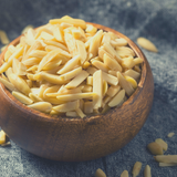 Small round timber bowl filled with Blanched Slivered Almonds on black cloth background.