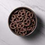 Bowl of Dark Chocolate Pretzels on white marble background.