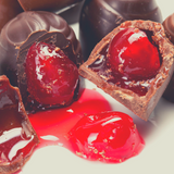 Close up of chocolate cherry liqour cracked open to show Glace Red Cherries inside.