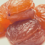 Close up of pile Glace Peaches whole, on white background.
