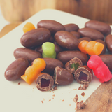 Chocolate Jelly Babies on marble and timber board, some cut open to expose jelly baby centre.