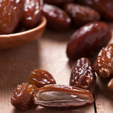 Close up of Organic Medjool Dates scattered on timber table.