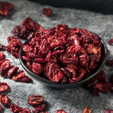 Organic Dried Cranberries in black ceramic bowl, on grey cloth.