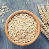 Rolled Oats Organic in timber bowl with wheat stalk sitting beside it. On concrete background.