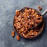Round basket full of Pecans on concrete background.