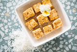Toasted Mallows in square white bowl, sitting on terazzo background with shredded coconut scattered nearby.