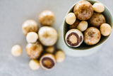 Close up of Moon Macadmias and raw macadamias in small tear drop shaped bowl.