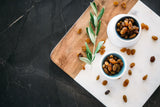 Two small bowls of plump Sultanas on marble chopping board.