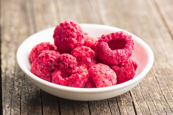 Freeze dried raspberries in a shallow white bowl