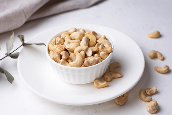 Health Benefits of Cashews - bowl of cashews on white background
