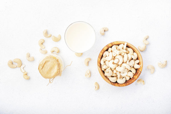 Glass of nut milk and cashews on a white background