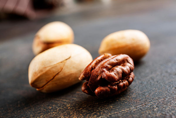 Close up shot of 1 shelled walnut and 3 walnut shells
