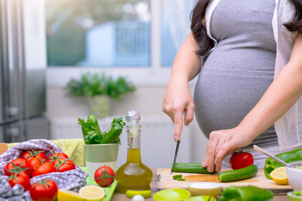 Pregnant woman cutting up Plant-based foods for fertility