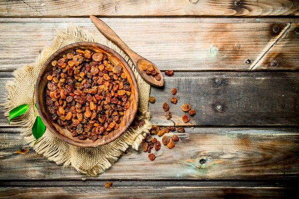 Bowl of sultanas on a wooden backdrop
