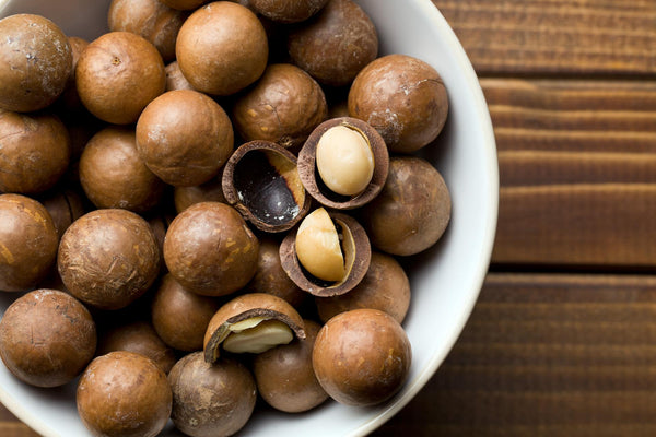 Bowl of macadamia nuts on a wooden backdrop