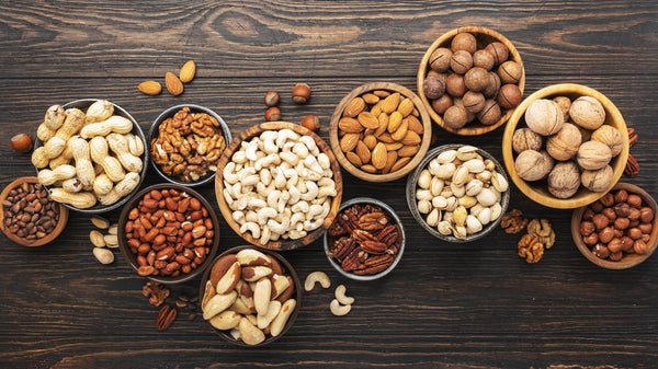 Variety of organic nuts in small bowls on a wooden background