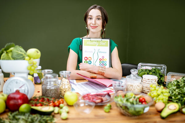 A woman sitting at a table of food with a personalised diet plan.