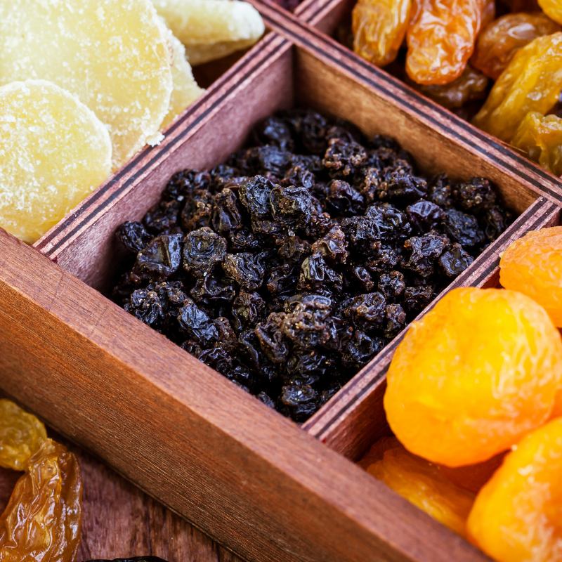 Close up of Currants in a timber dried fruit gift box, next to various dried fruit.