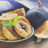 Turkish Dried Figs sitting on a silver dish next to purple whole fig. 