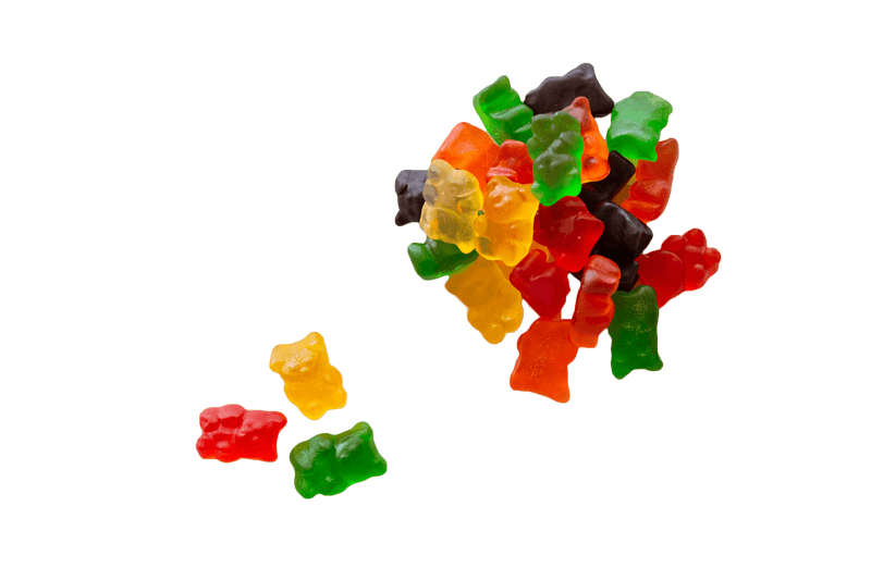 Small pile of Gummi Bears sitting next to a yellow, red and green gummy bear.