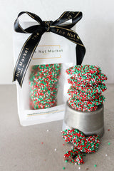 Giant Chocolate Freckles Christmas in gift bag, behind stack of freckles. Red, white and green scattered 100's and 1000's.
