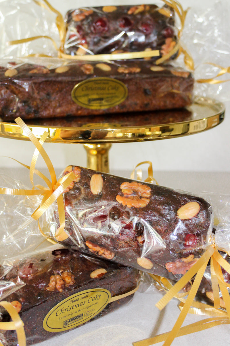 Christmas Cakes small and large, wrapped with gold ribbon, sitting on gold cake plate. 
