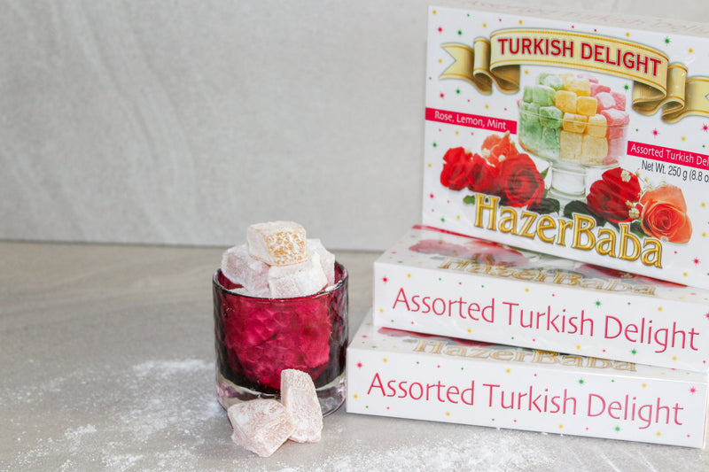 Boxes of Hazer Baba Assorted Turkish Delight sitting next to red glass jar of Turkish Delight pieces spilling over.