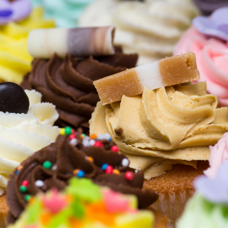 Close up of Jersey Caramel on top of cupcake, surrounded by colourful iced cupcakes. 