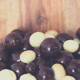 Close up of Dark Chocolate Macadamias on timber board.