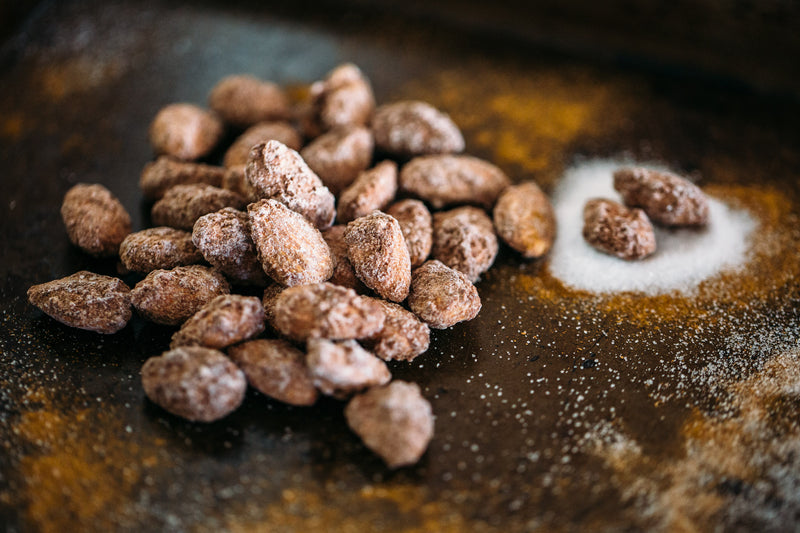 Small pile of Roasted Cinnamon Almonds on dark background. Dusted with sugar and cinnamon.