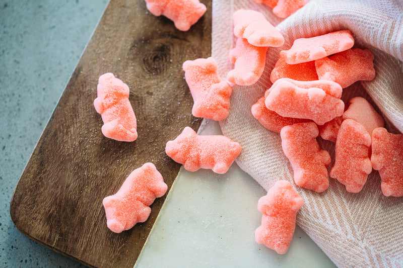 Strawberry Piglets spilled across pink tea towel on timber and marble board.