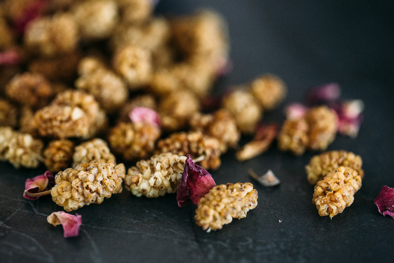 Close up of Organic Dried Mulberries scattered with rose petals.